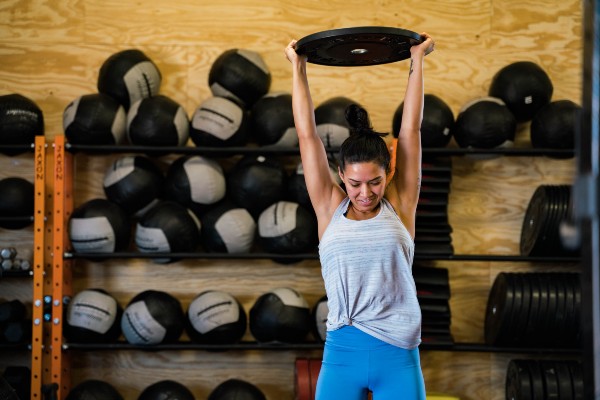 woman in crossfit class lifting weight over her head
